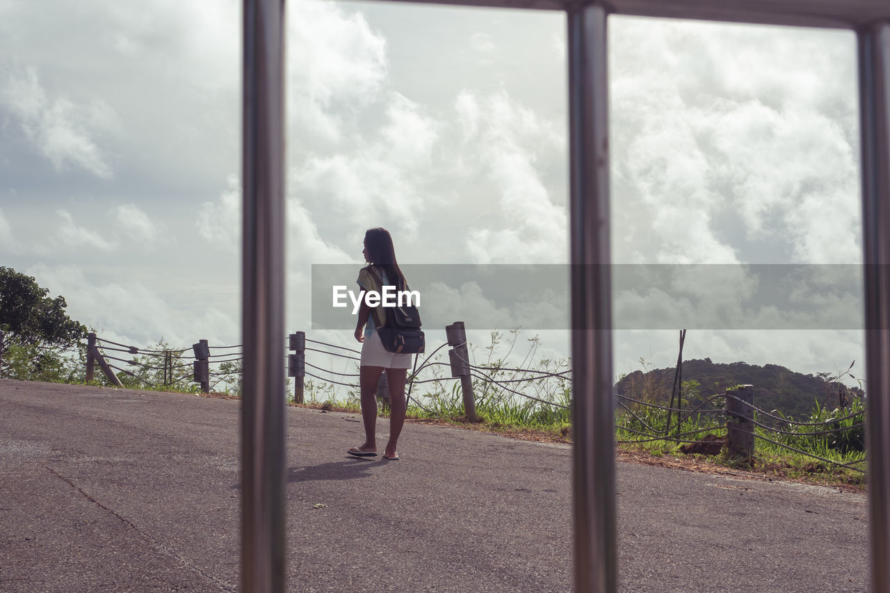 FULL LENGTH REAR VIEW OF WOMAN STANDING AGAINST SKY