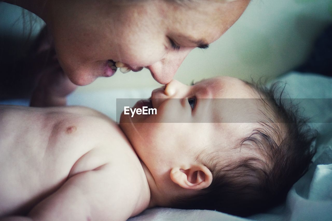 Close-up of mother with newborn baby at bed in home