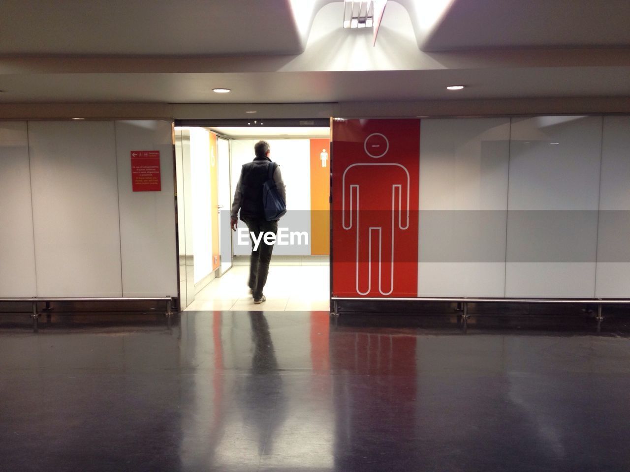 FULL LENGTH OF WOMAN WALKING IN ILLUMINATED CORRIDOR