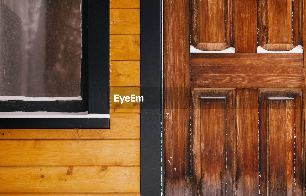 Closeup of wooden house with door and window.