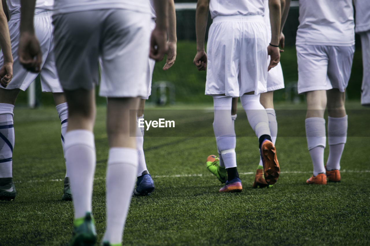 Low section of people playing soccer on field