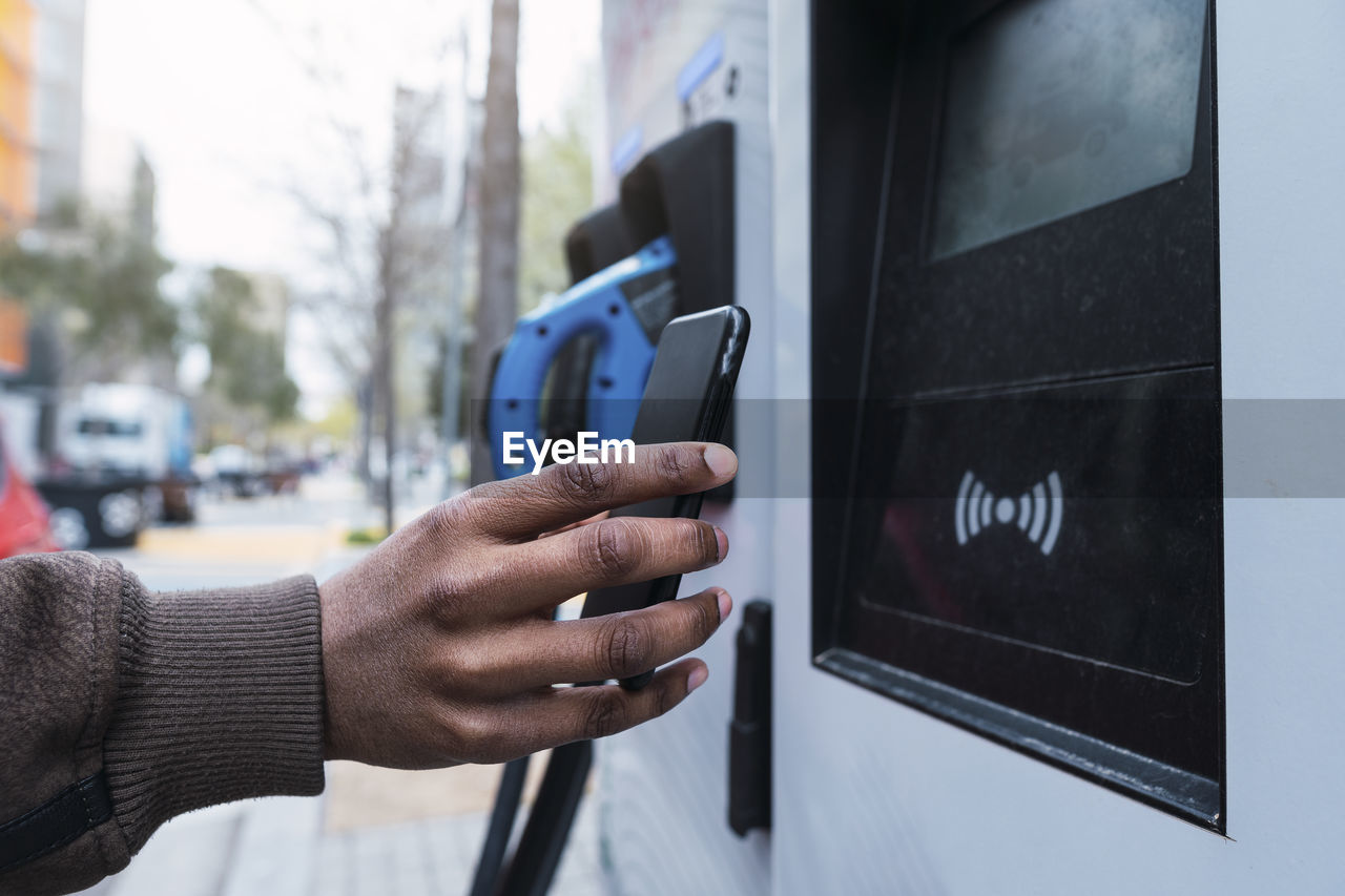 Hand of man paying through smart phone at charging station