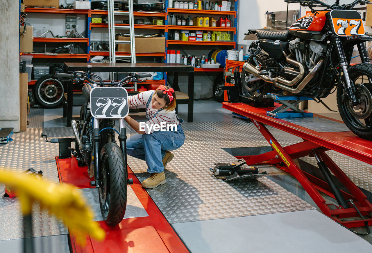 Mechanic woman checking custom motorcycle on factory