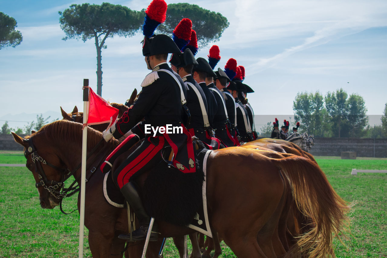 GROUP OF PEOPLE RIDING HORSE ON FIELD