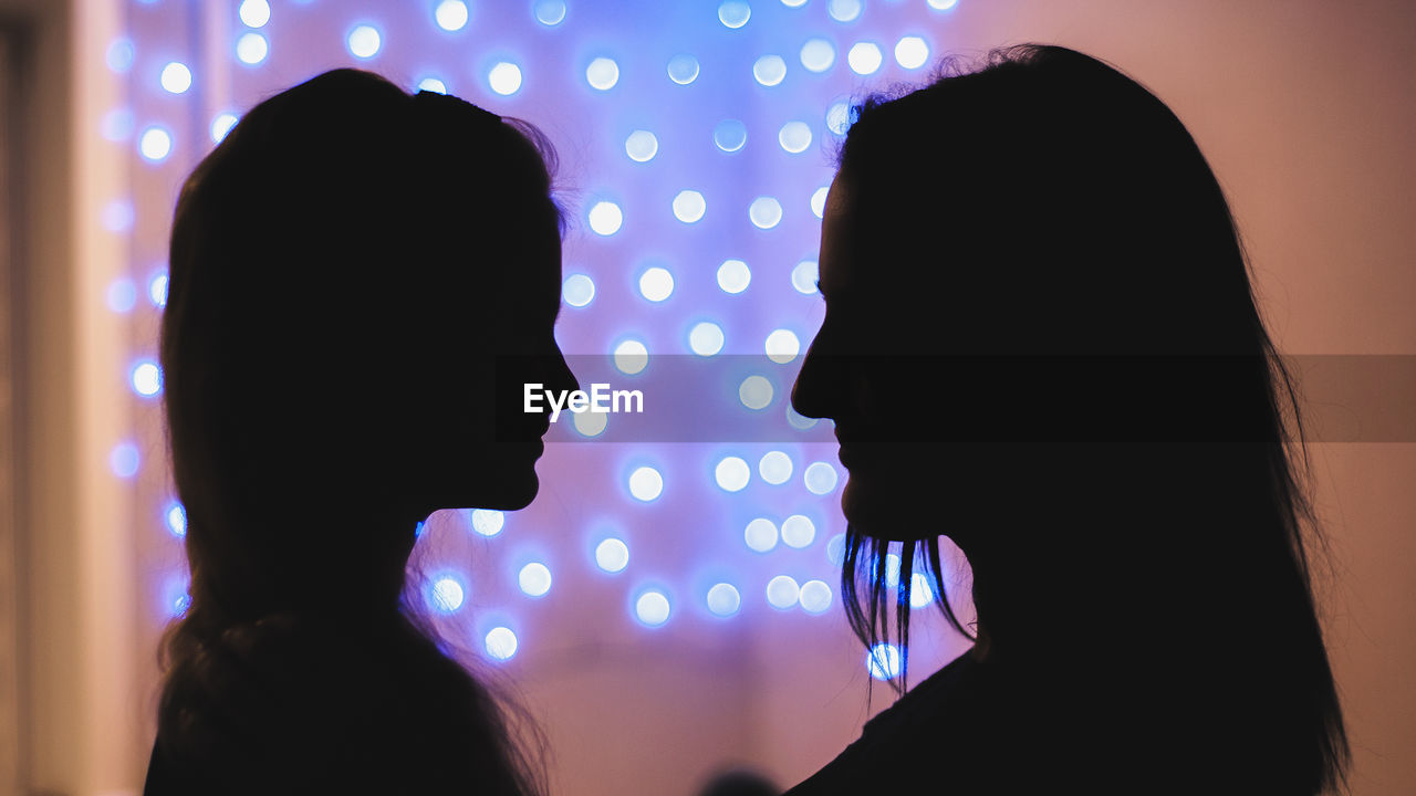 Silhouette lesbian couple against illuminated background