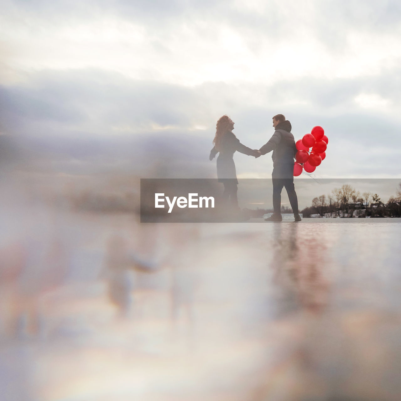 REAR VIEW OF COUPLE STANDING IN WATER