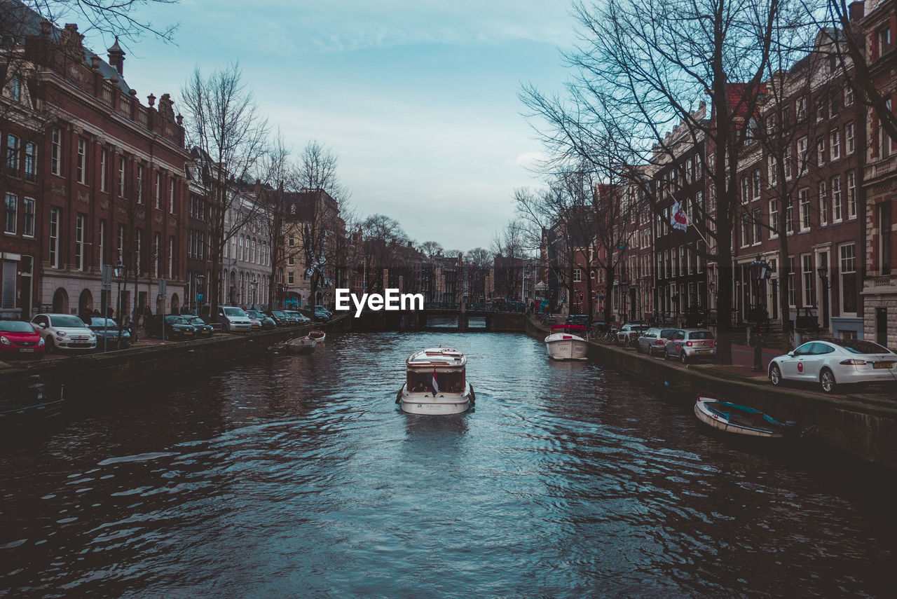 Boats in canal amidst buildings in city