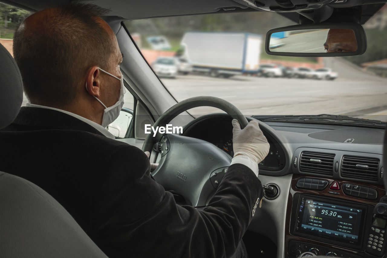 Rear view of man wearing gloves while driving car