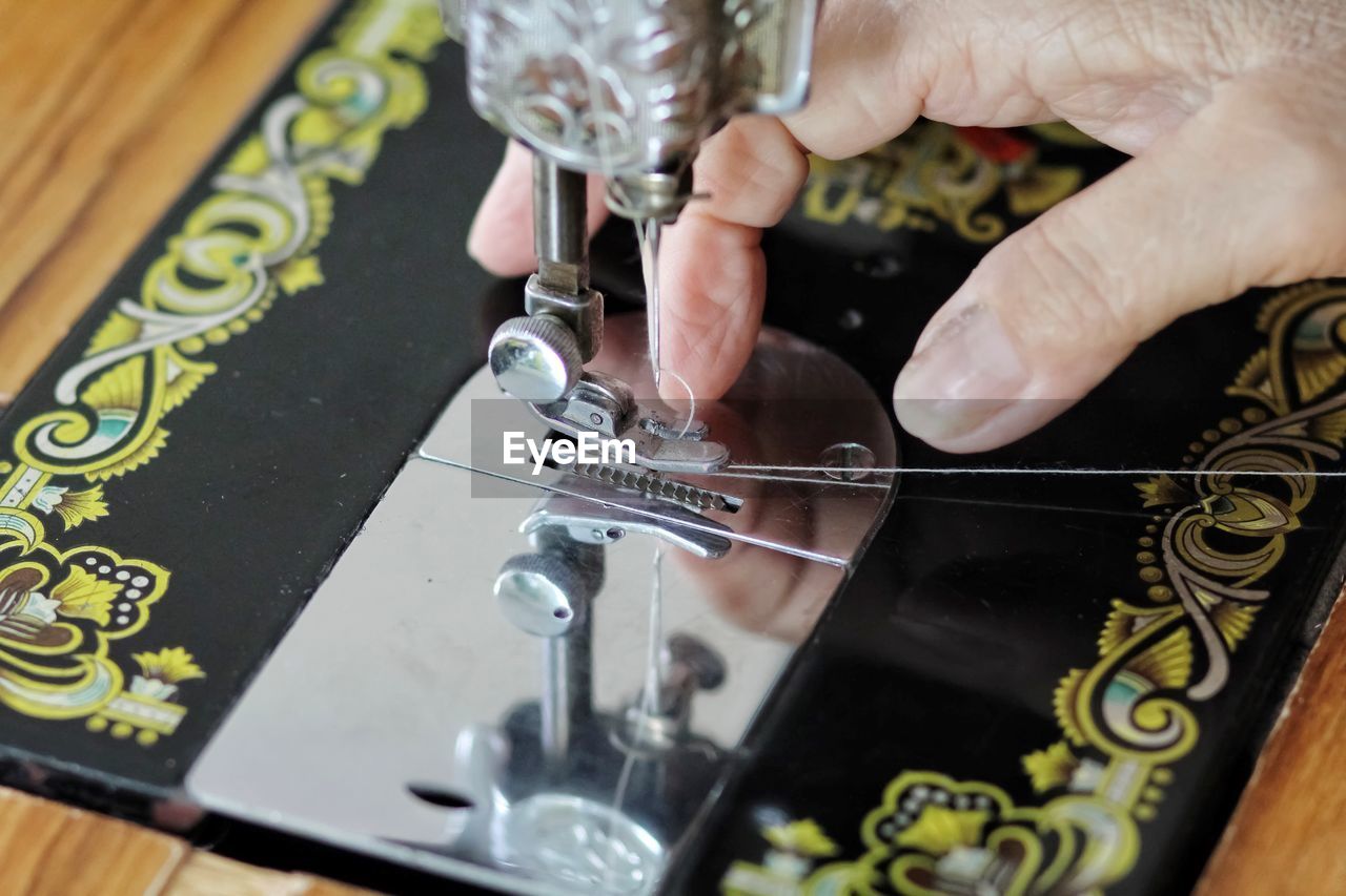 Cropped hand of tailor using sewing machine