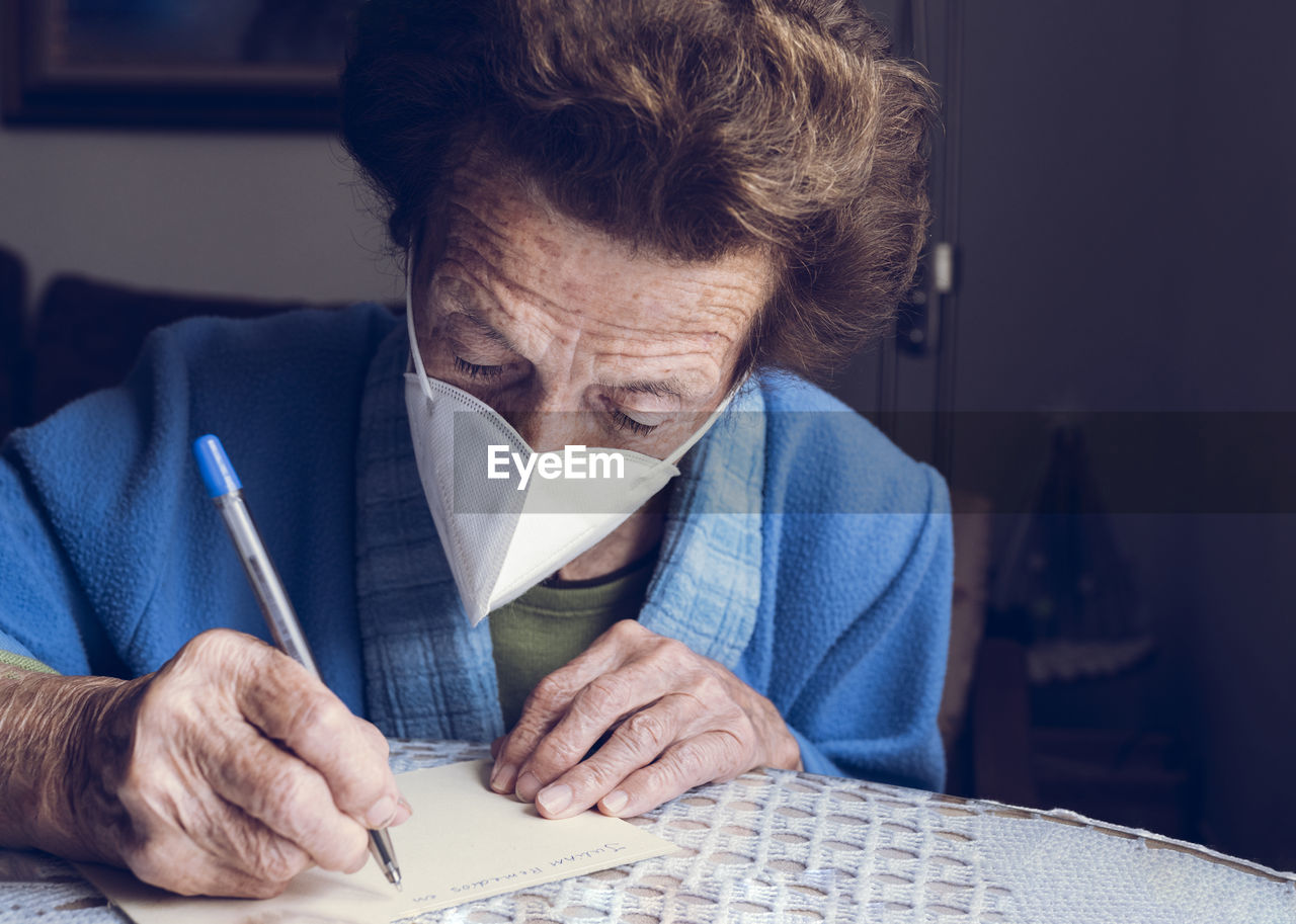 Senior woman writing on paper at home