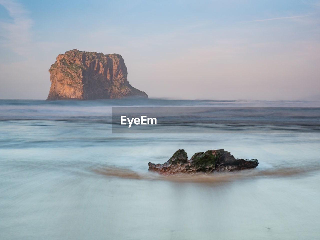 Rock formation on sea shore against sky