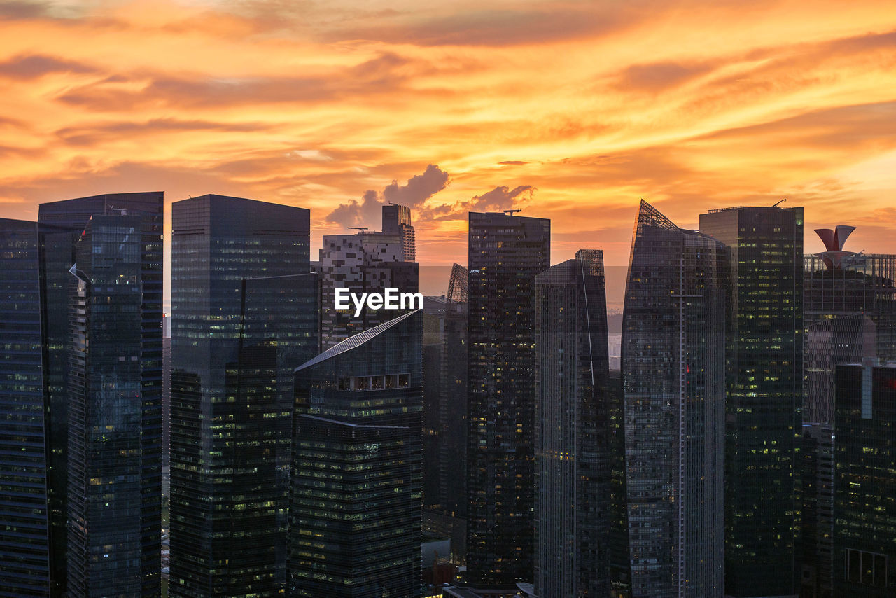 Modern buildings in city against sky during sunset