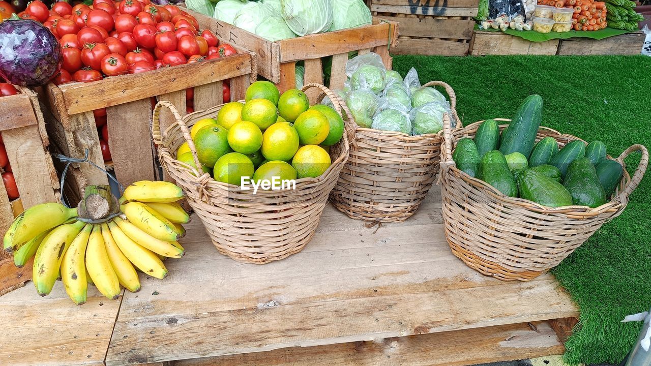 Fresh banana, lime, guava, green chayote, cucumbers red tomatoes in rattan wicker baskets