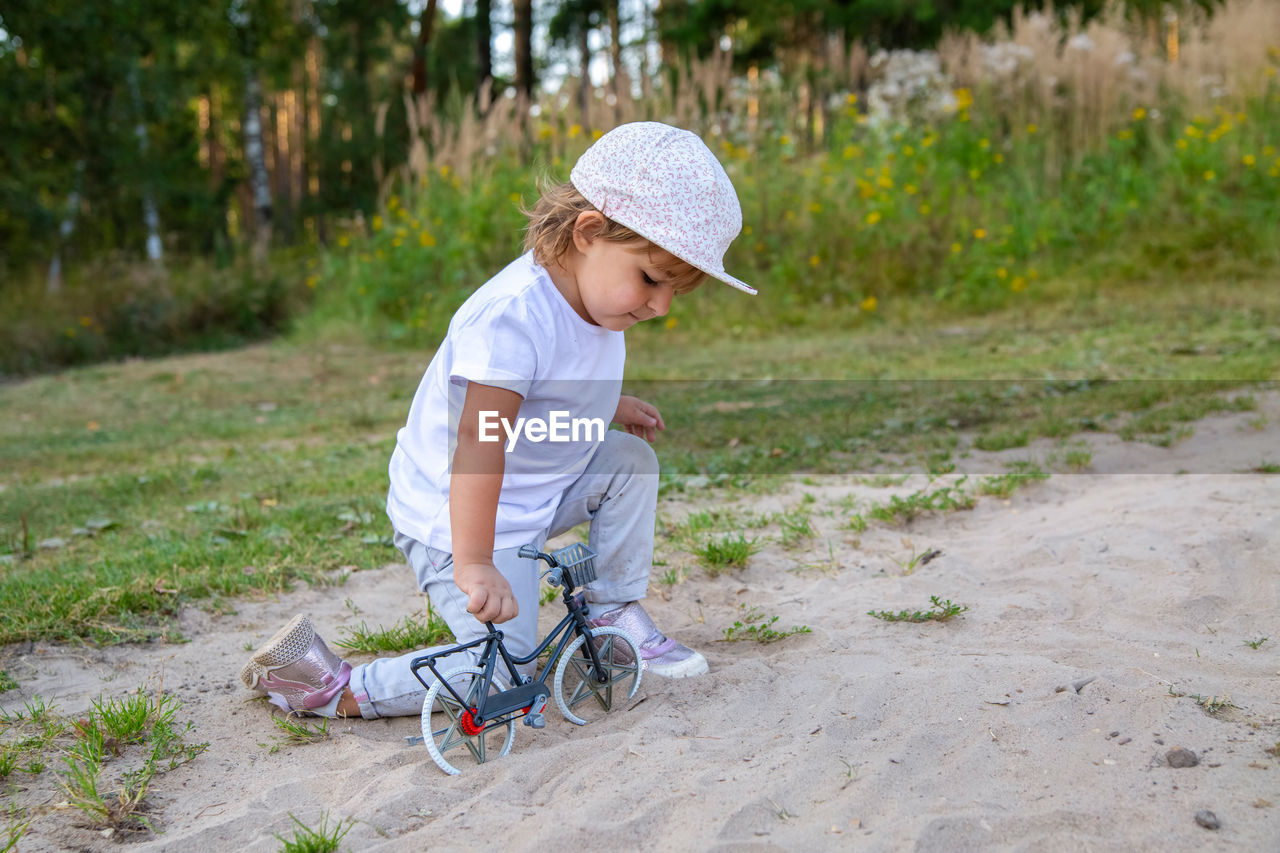 SIDE VIEW OF CUTE BOY WITH BICYCLE IN PARK