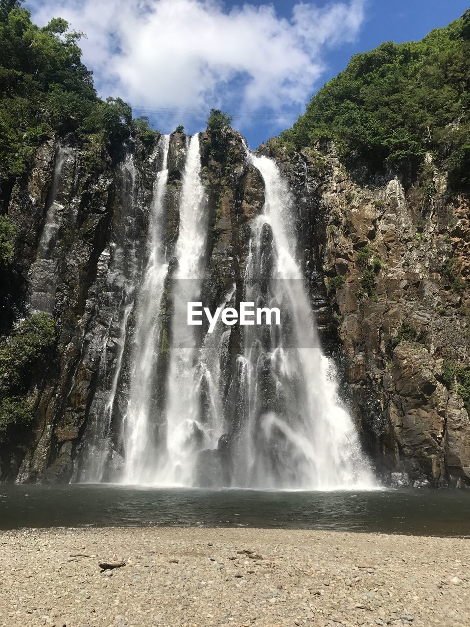 LOW ANGLE VIEW OF WATERFALL AGAINST TREES