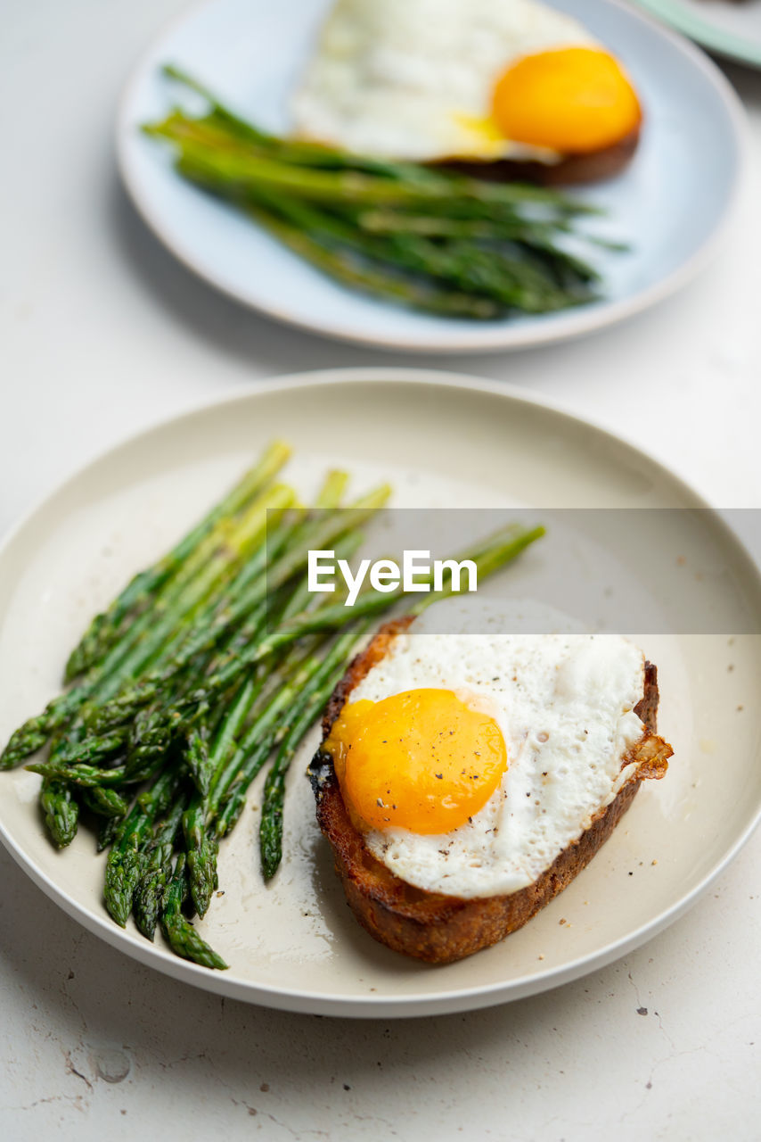 food, food and drink, healthy eating, egg, plate, wellbeing, meal, fried egg, vegetable, fried, dish, egg yolk, freshness, produce, no people, asparagus, indoors, breakfast, sunny side up, studio shot, green, herb, close-up