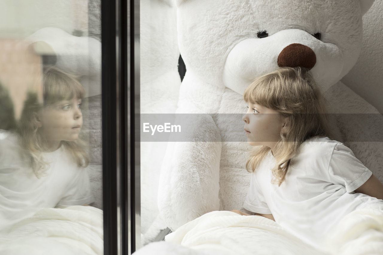 Girl of 5 years is looking at the window in the time of pandemic