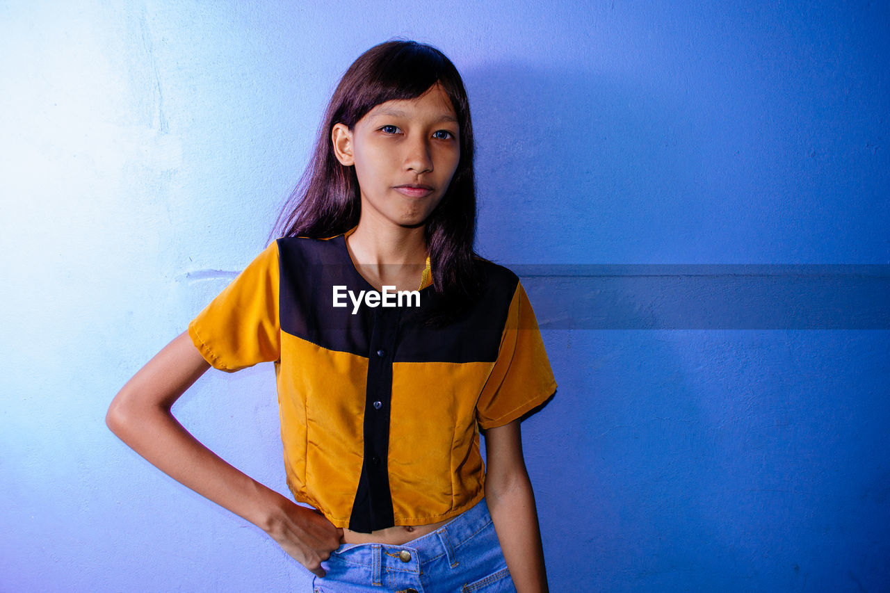 Young woman standing against wall