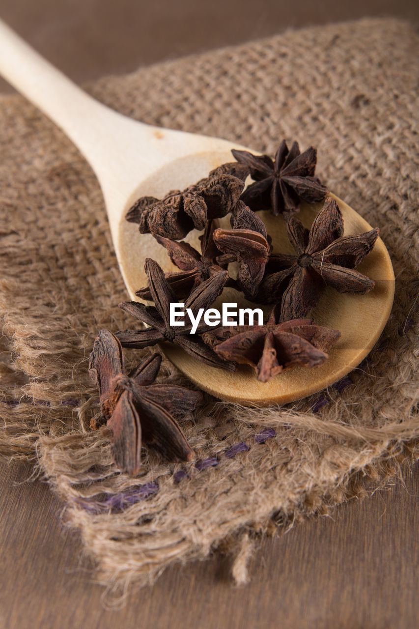 Close-up of star anise in wooden spoon with burlap on table