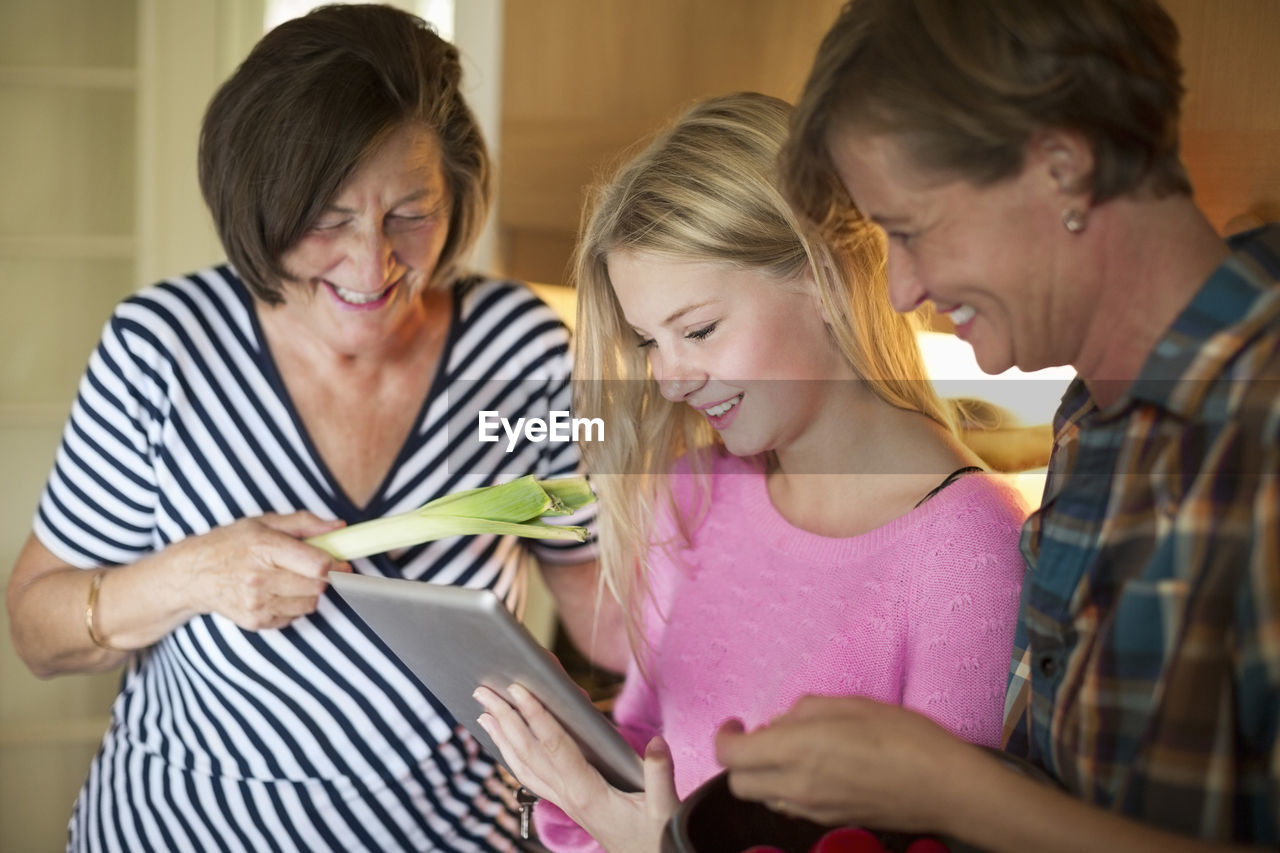 Three generation females searching recipe on digital tablet in kitchen