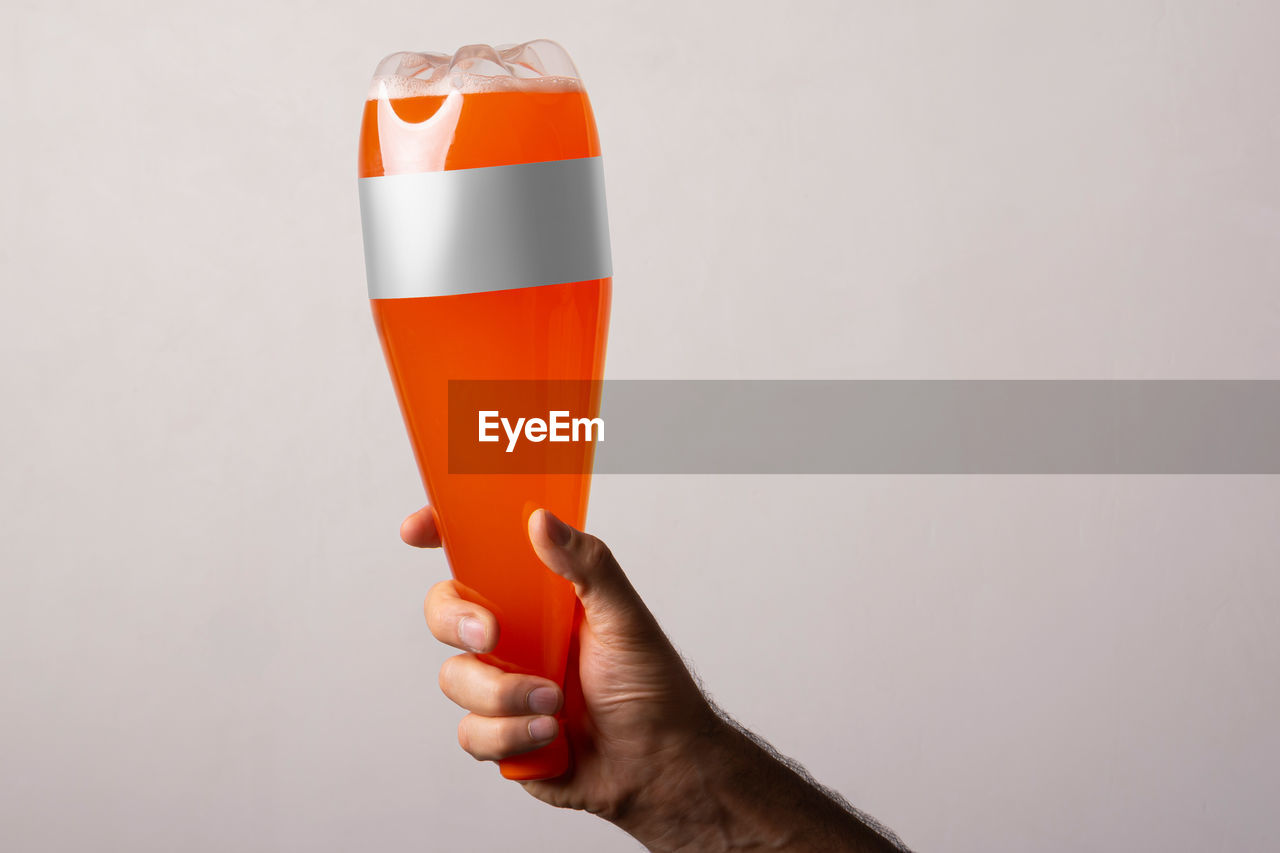 hand, holding, studio shot, food and drink, drink, refreshment, one person, indoors, alcohol, copy space, adult, glass, orange, red, close-up, orange color, celebration, soft drink, white background