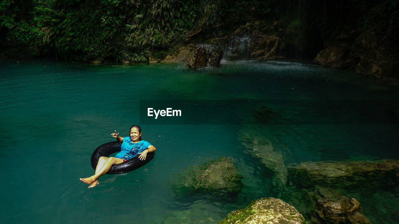 Portrait of smiling mature woman on inflatable ring in river