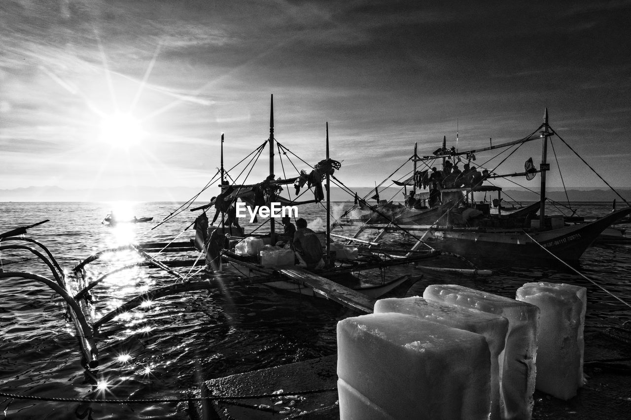 People fishing in sea against sky