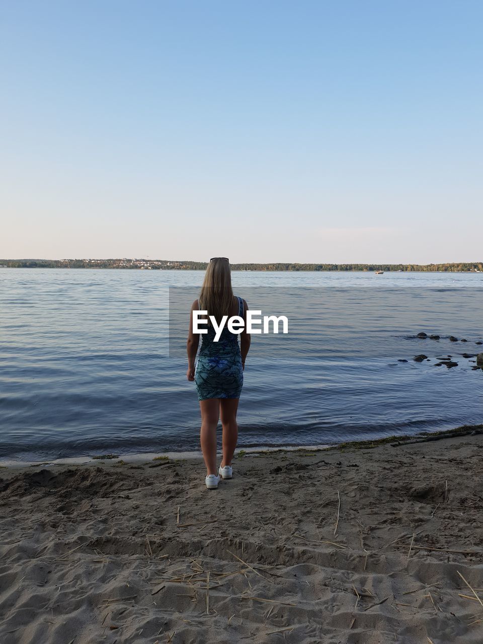 Rear view of woman standing at beach against sky