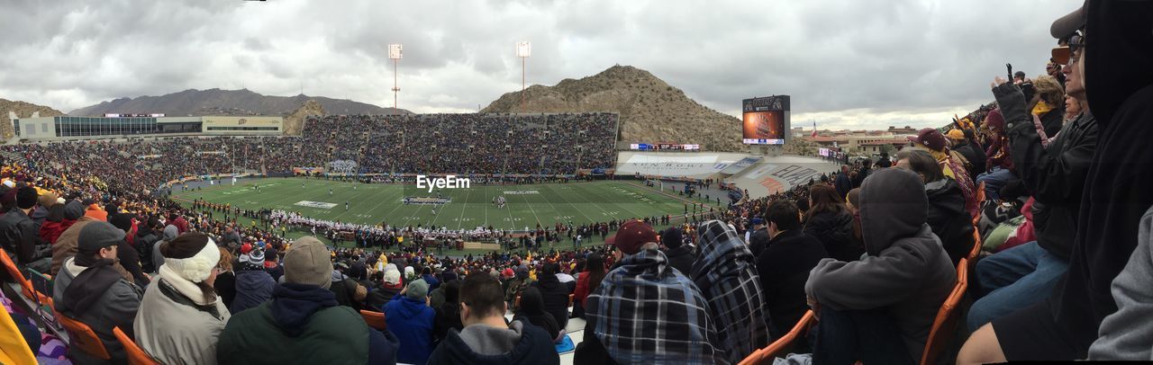 PANORAMIC VIEW OF CROWD ON TOWN AGAINST SKY