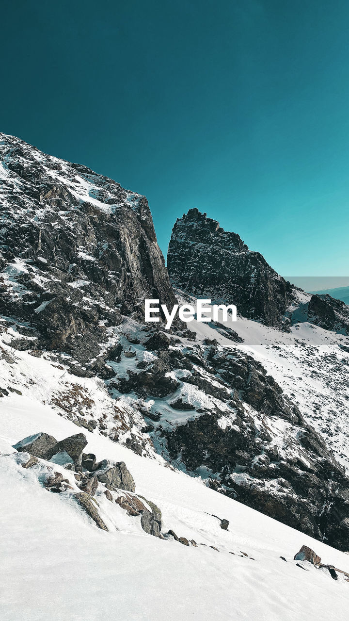 Scenic view of snowcapped mountains against clear blue sky