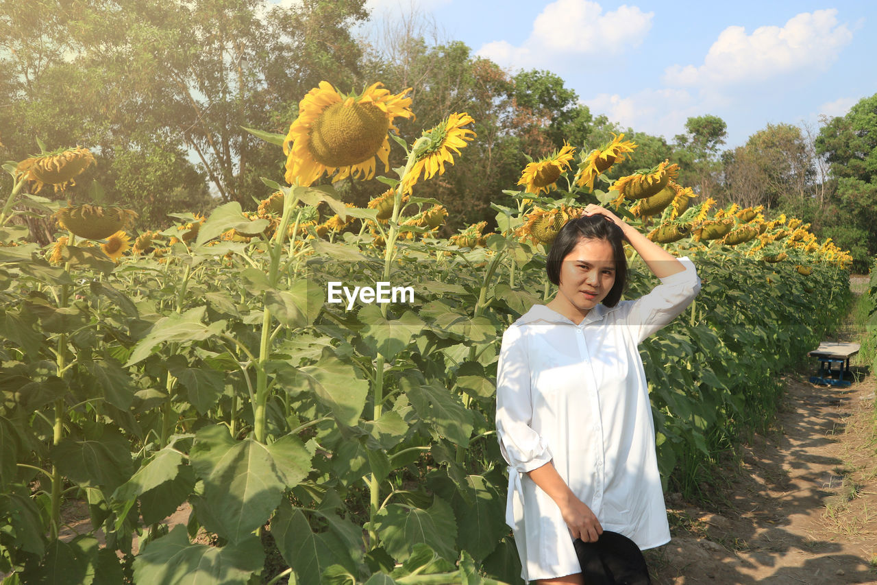 Asian woman standing among the field of sunflower