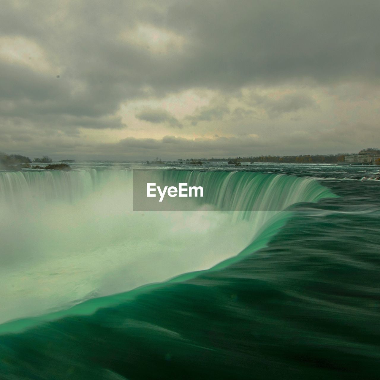 SCENIC VIEW OF WATERFALL AGAINST CLOUDY SKY