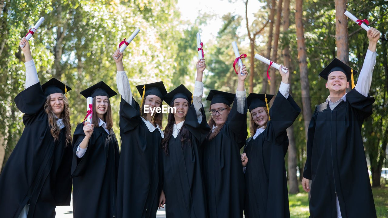 rear view of woman wearing graduation gown standing in park