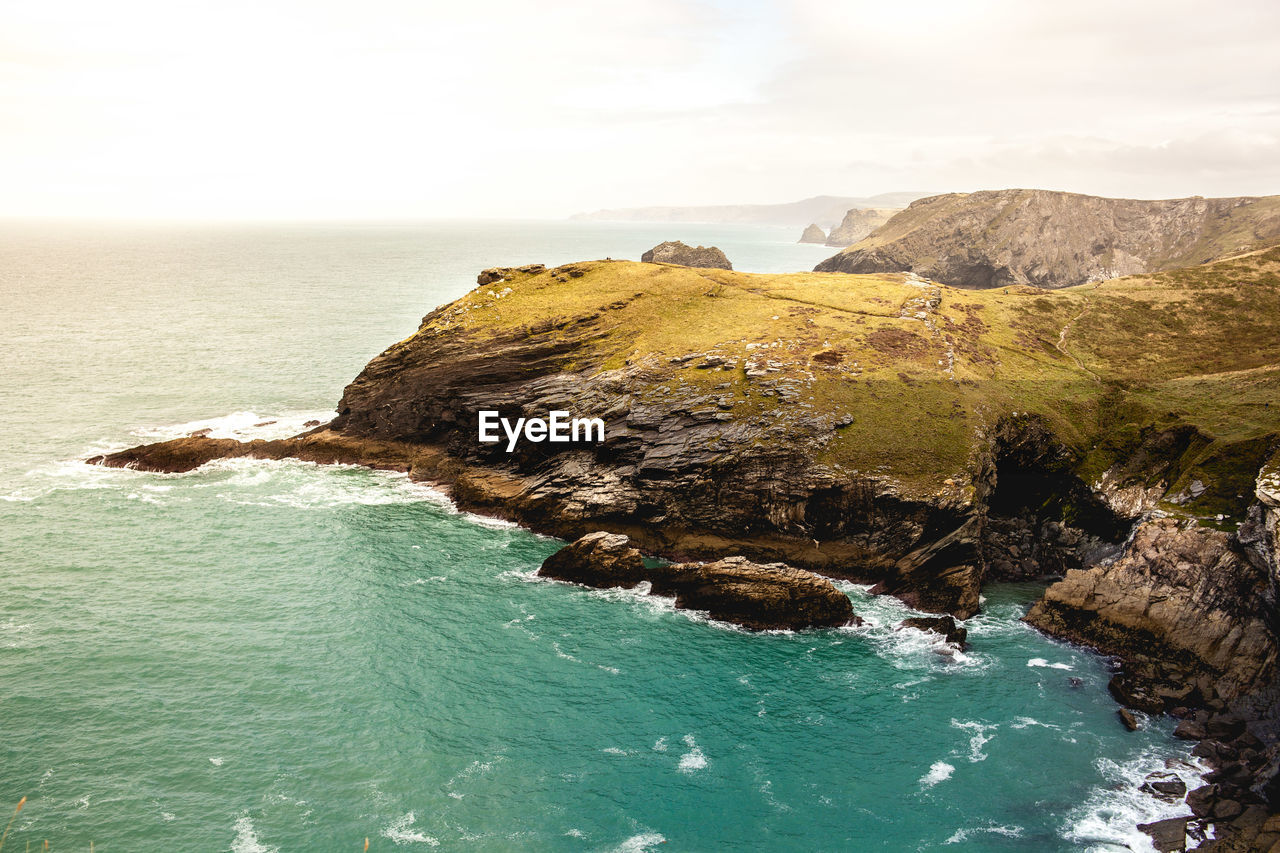 Scenic view of sea by cliff against sky