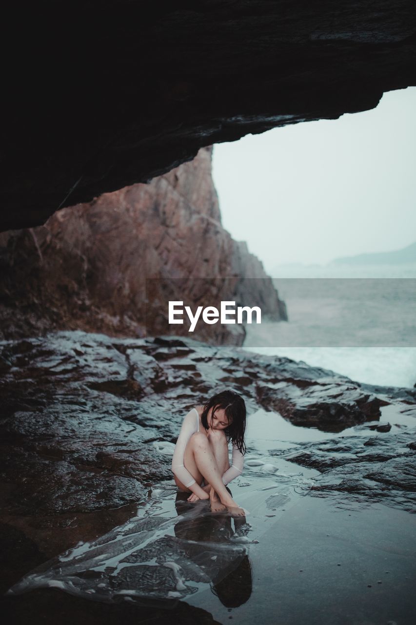 FULL LENGTH OF WOMAN ON ROCK AT SEA