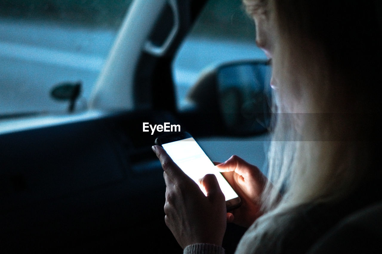 Cropped image of woman using smart phone in car