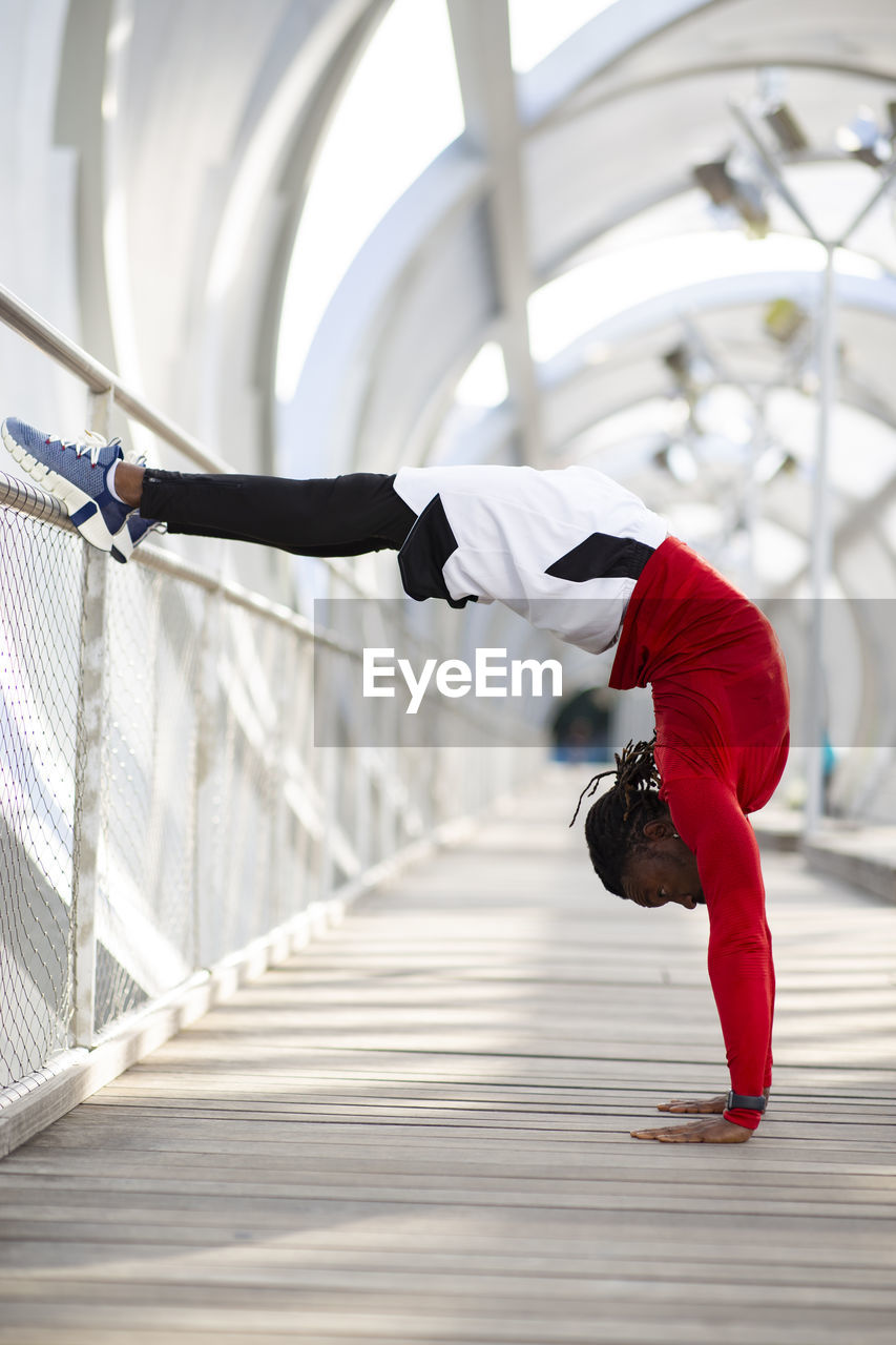 Athlete doing handstand while exercising on walkway