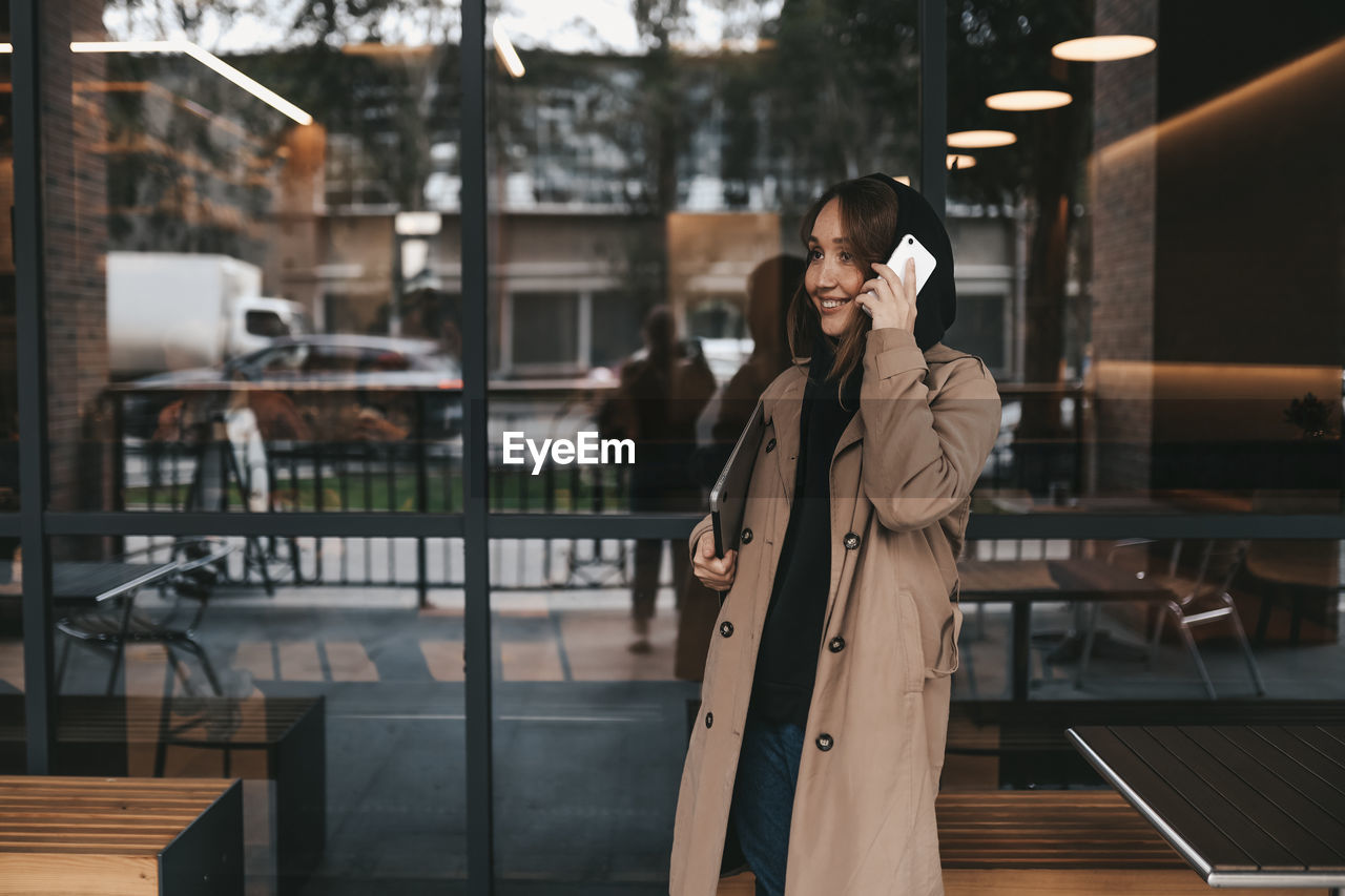 Adult business woman freelancer works using wireless technology talking on the phone sitting in cafe