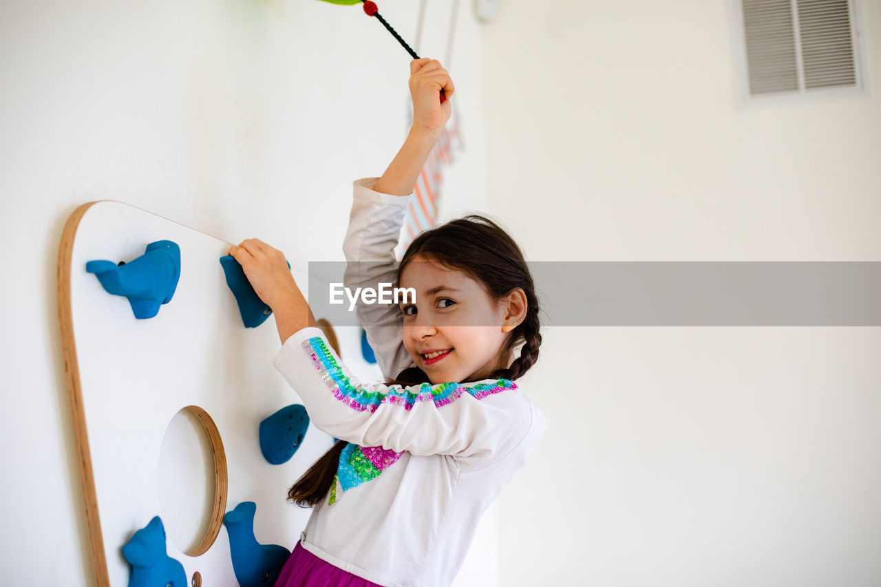 Portrait of smiling girl standing against wall