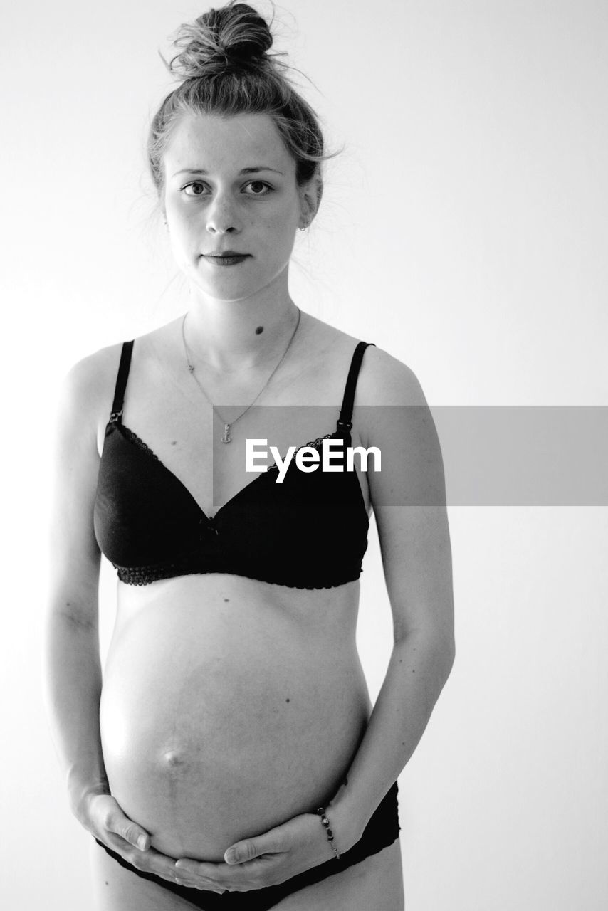 Portrait of pregnant woman standing against white background