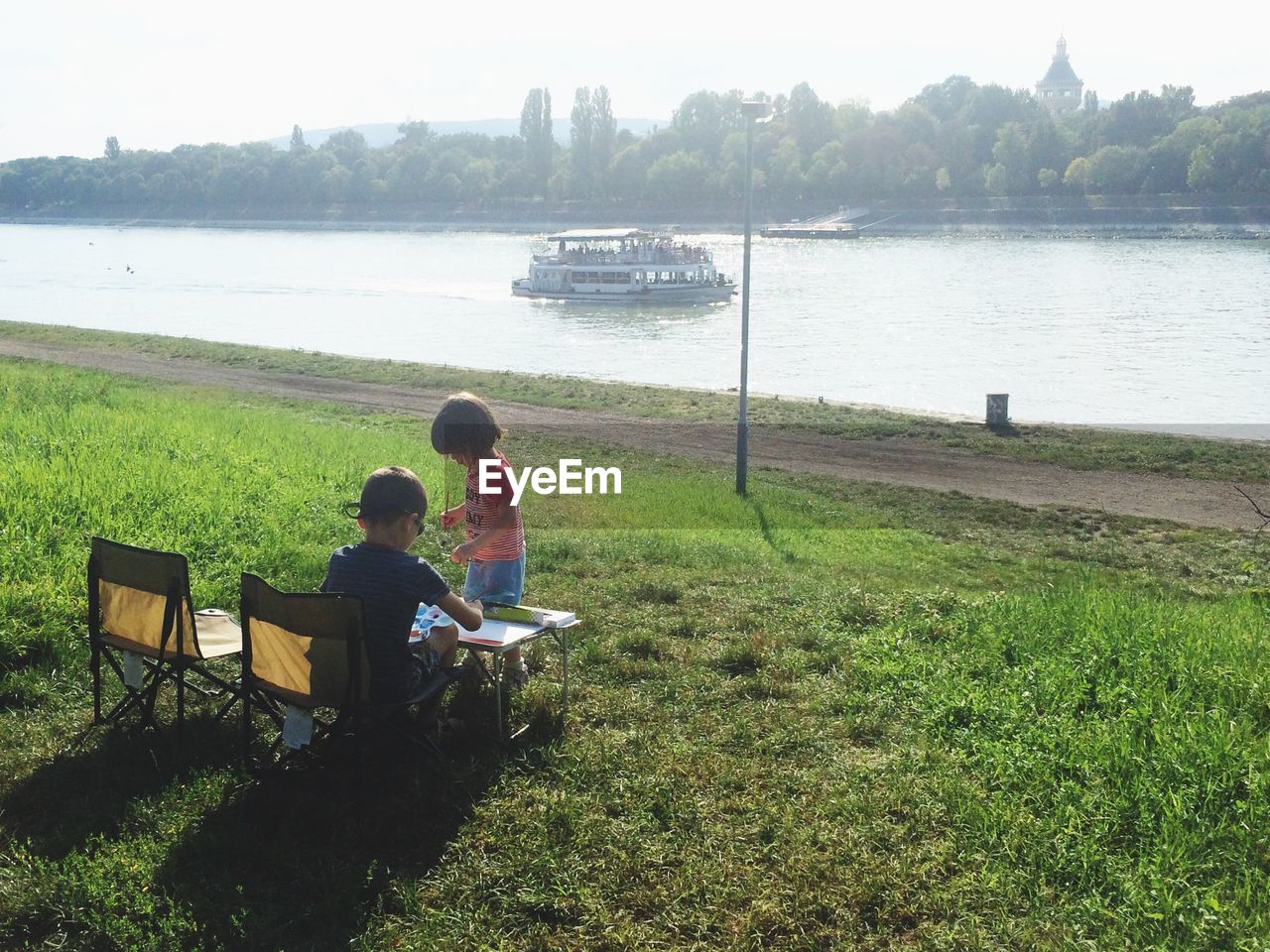 REAR VIEW OF MAN SITTING ON BENCH IN PARK