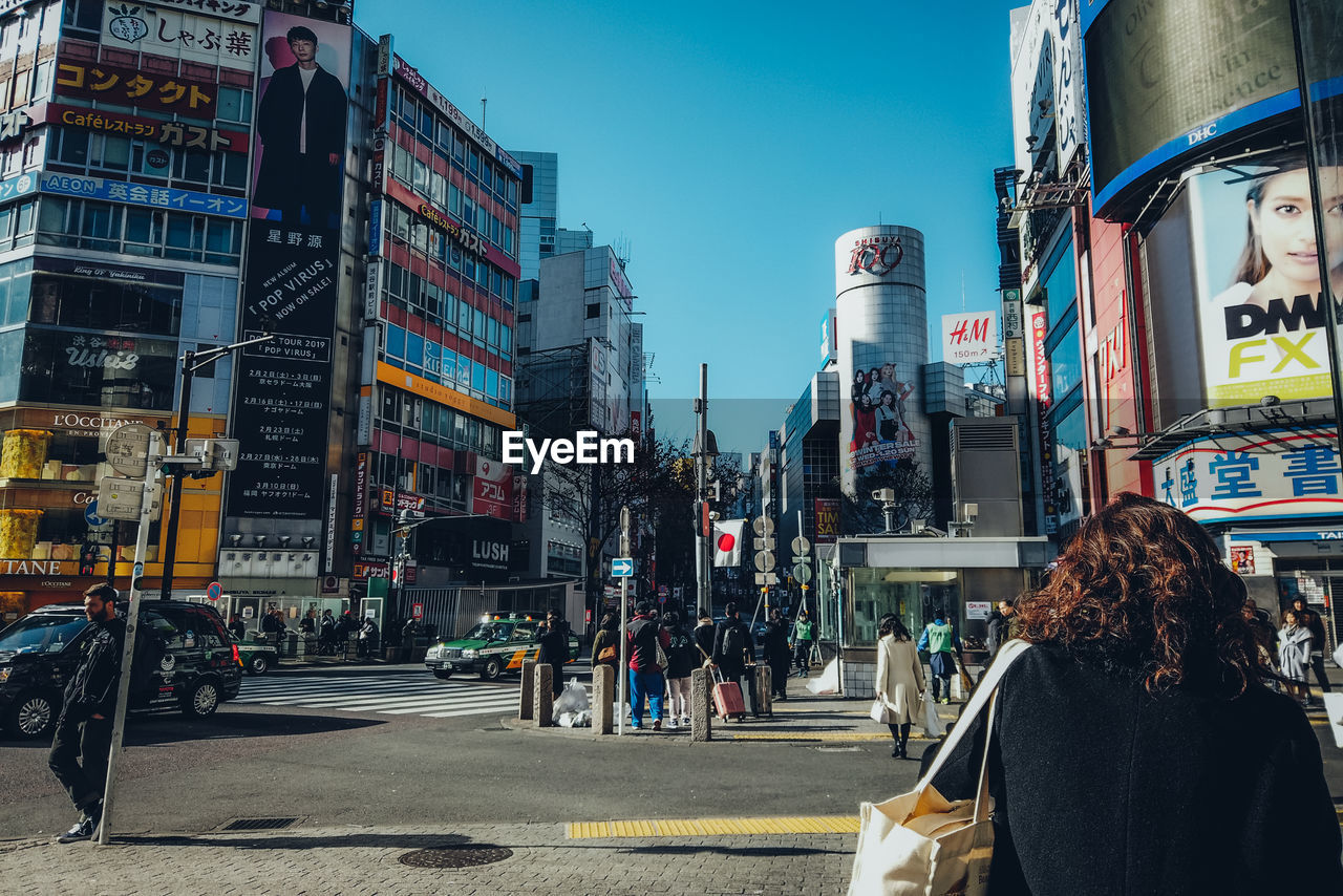 PEOPLE ON STREET AMIDST BUILDINGS IN CITY