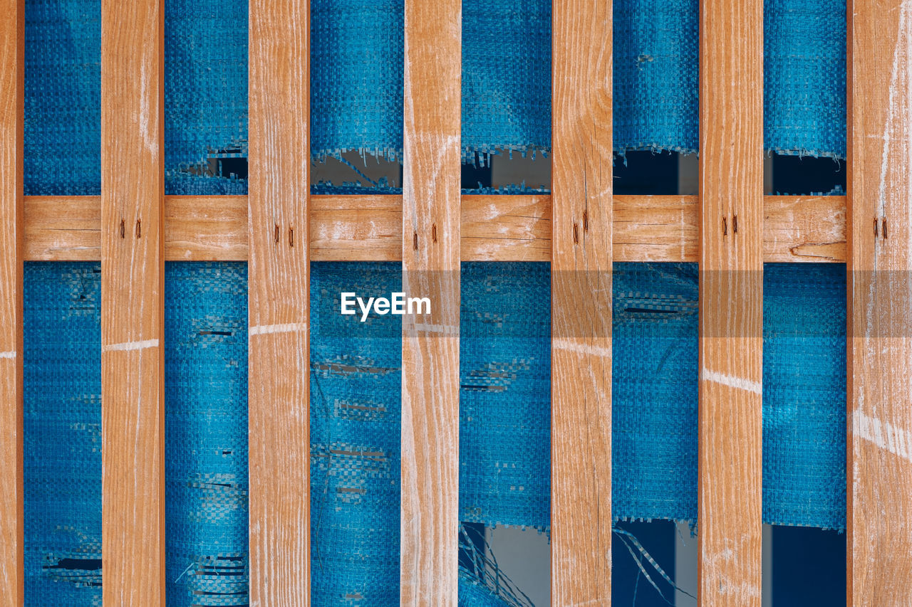 Full frame shot of wooden fence in front of blue plastic cover