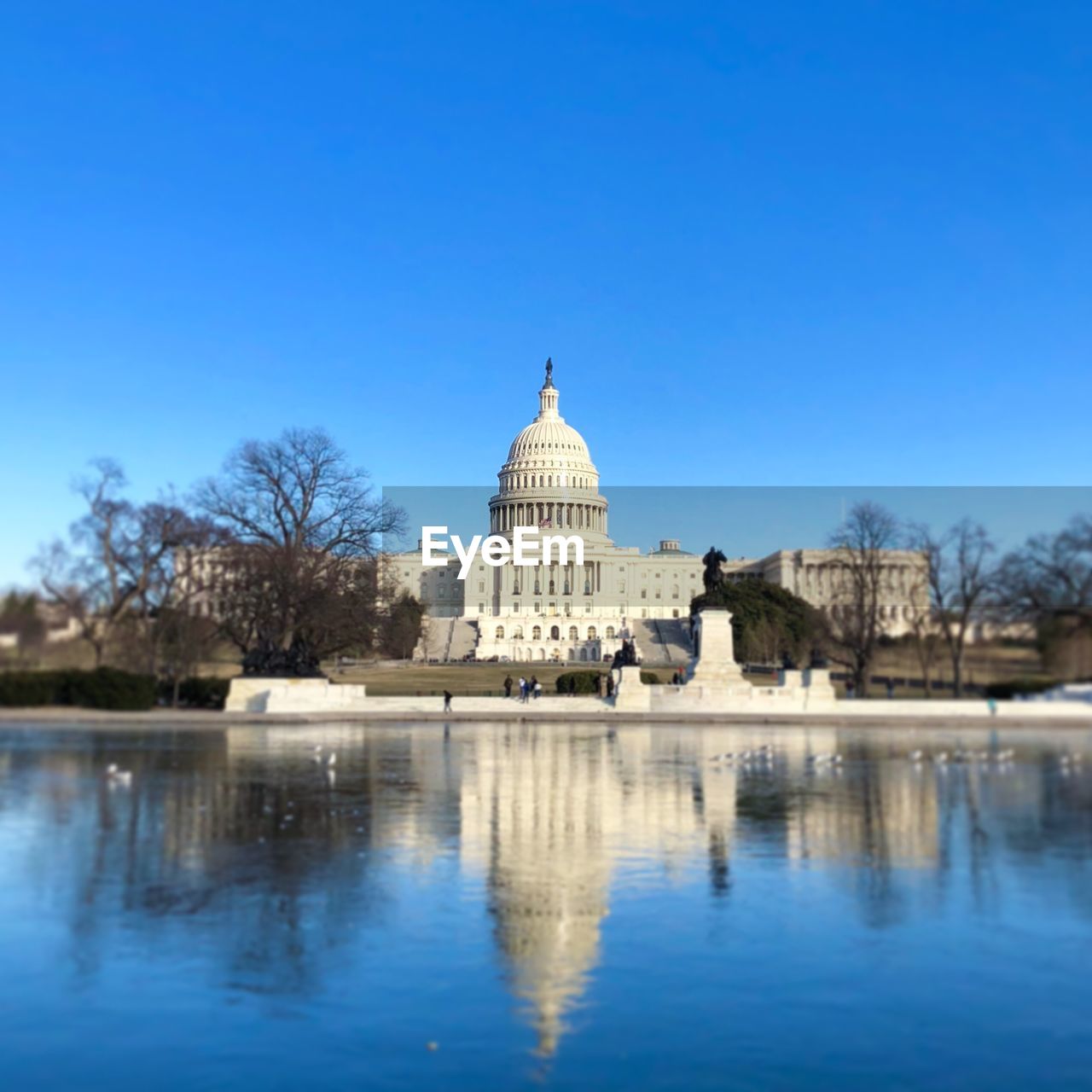 Reflection of us capital  in water against clear blue sky