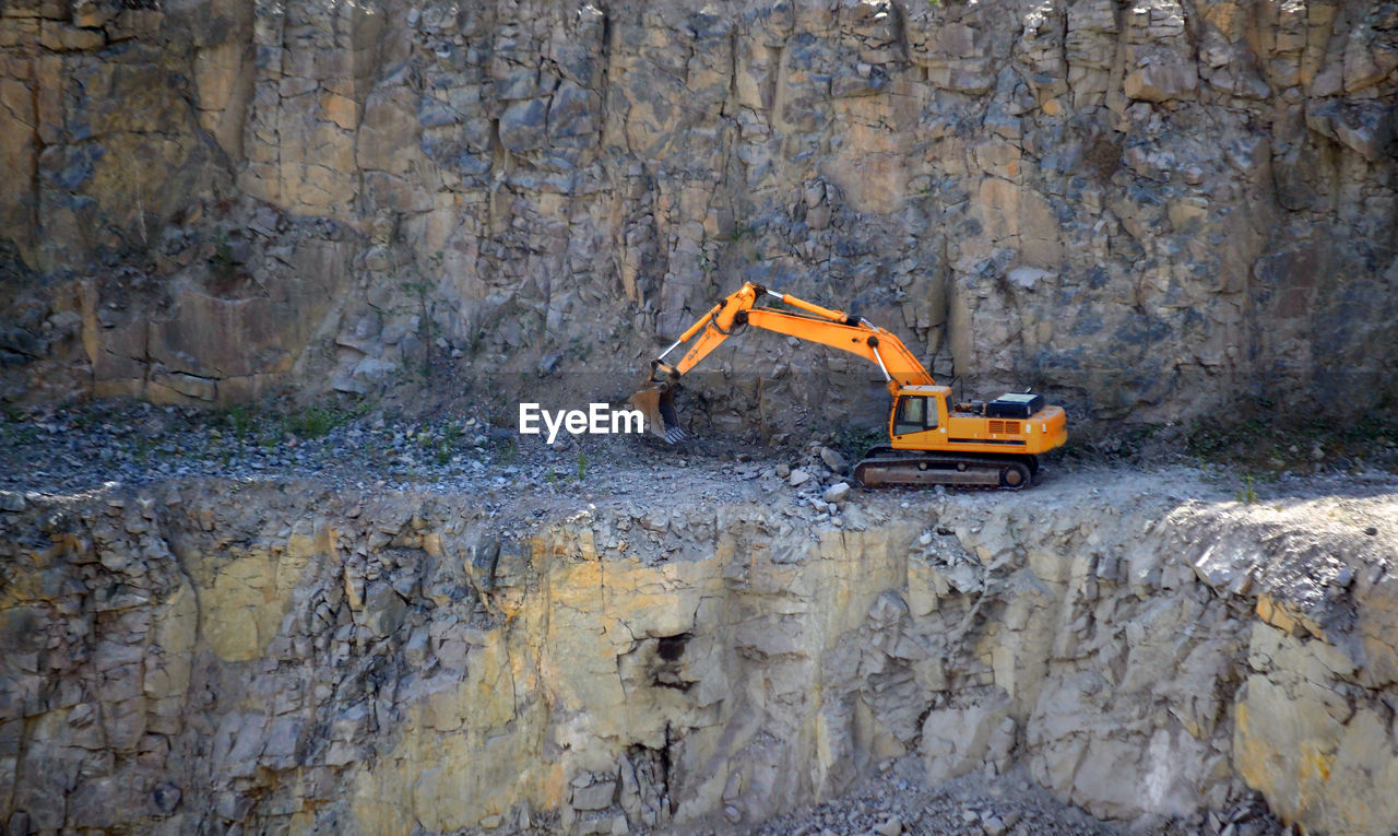 CONSTRUCTION WORKING ON ROCK BY WALL