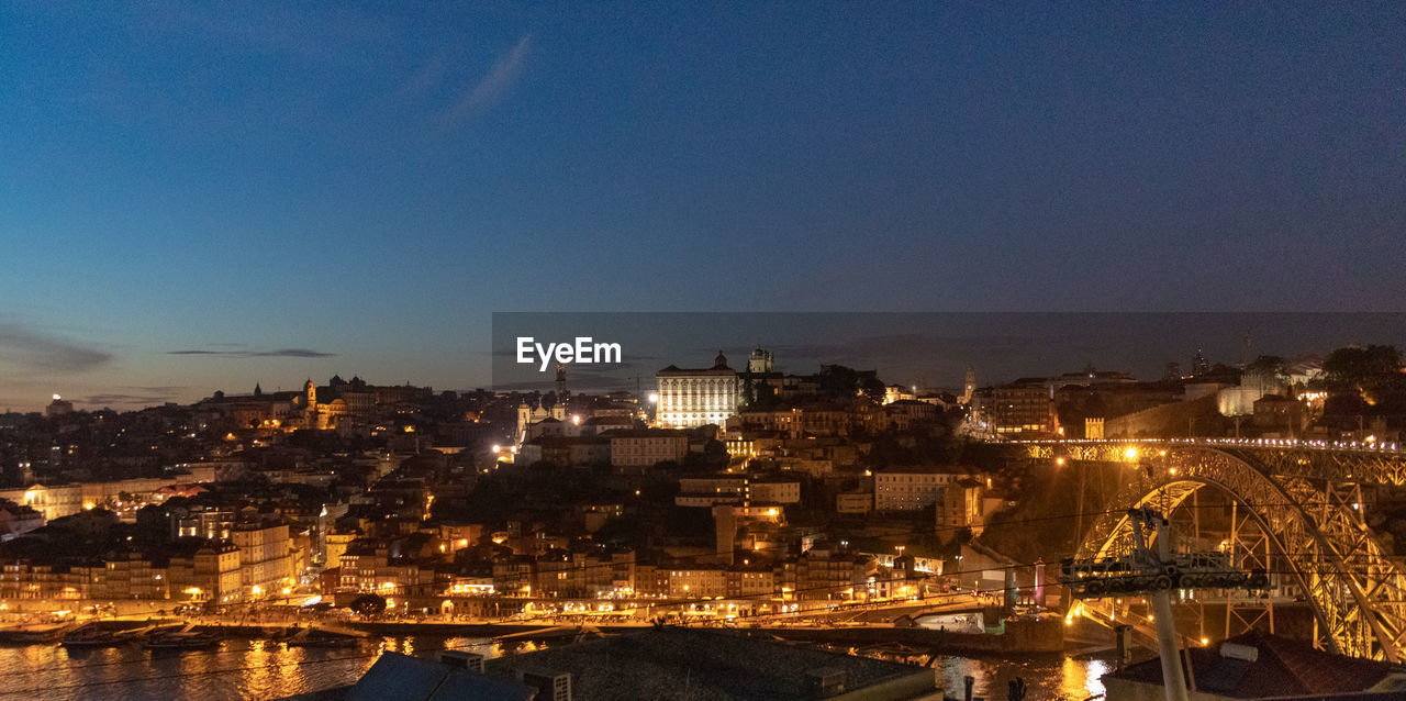 HIGH ANGLE VIEW OF ILLUMINATED CITY BUILDINGS AGAINST SKY AT NIGHT