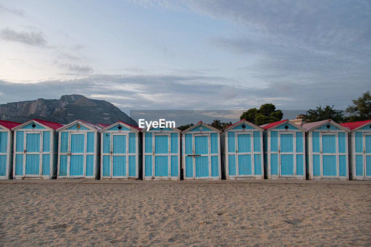 Beach huts by sea against sky. small blue houses in a row. italian vacation