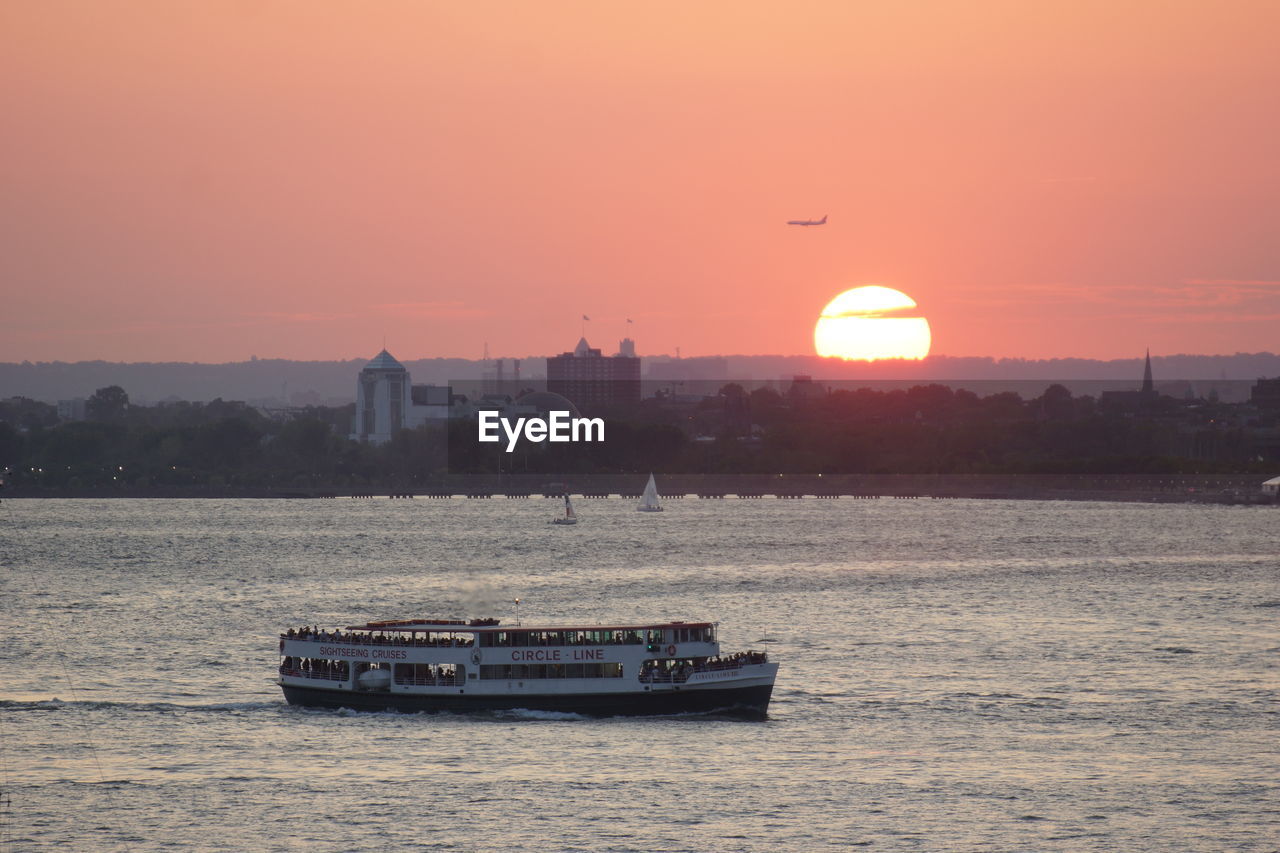 BOAT SAILING IN SEA AGAINST SUNSET SKY