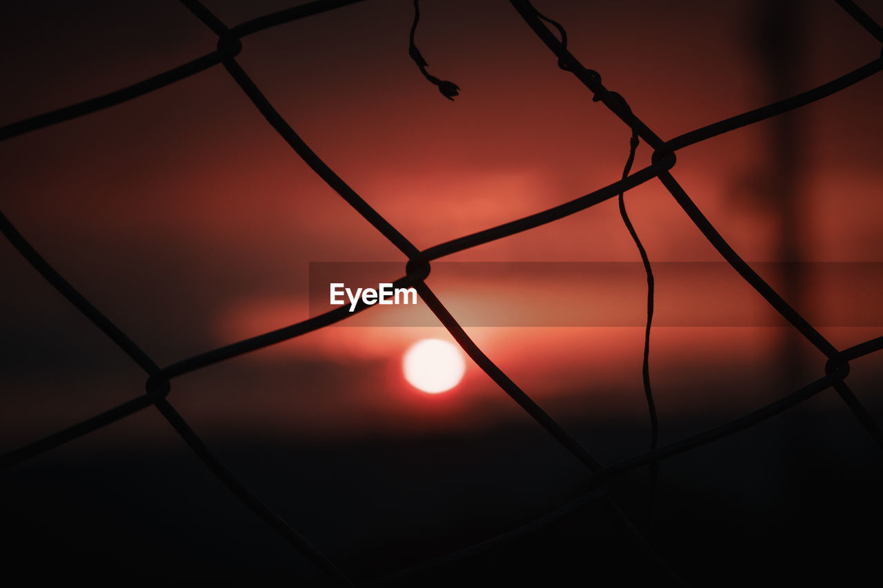 Close-up of silhouette fence against sky during sunset