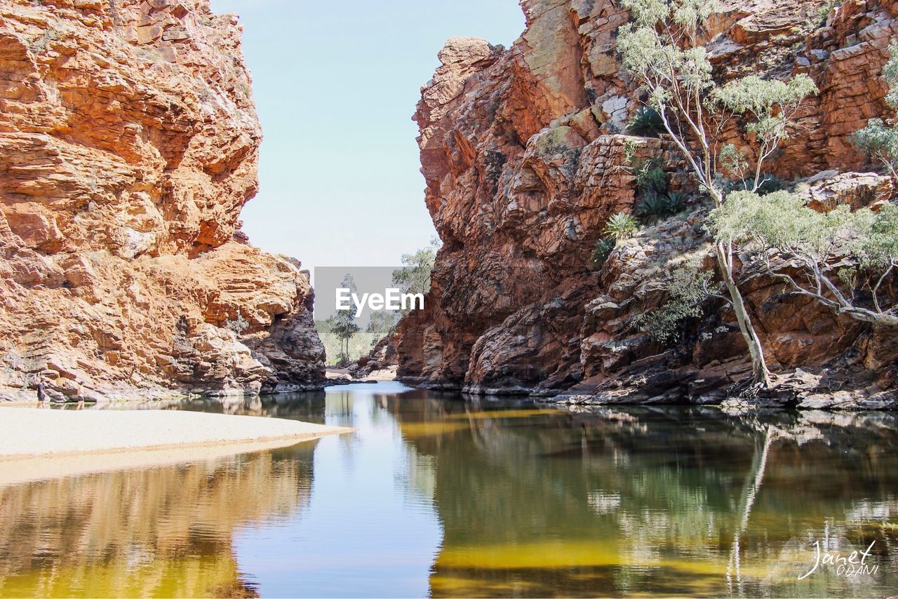 Rock formations by lake against sky